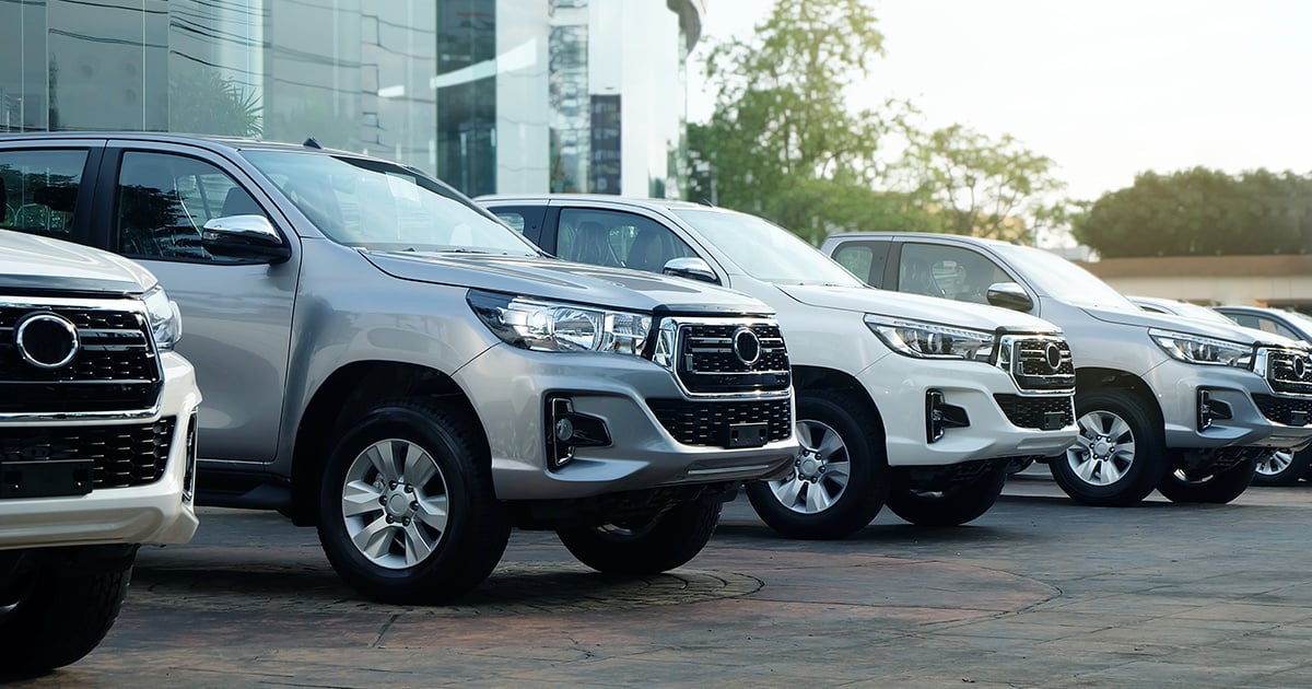 A row of new cars parked outside in front of a dealership.