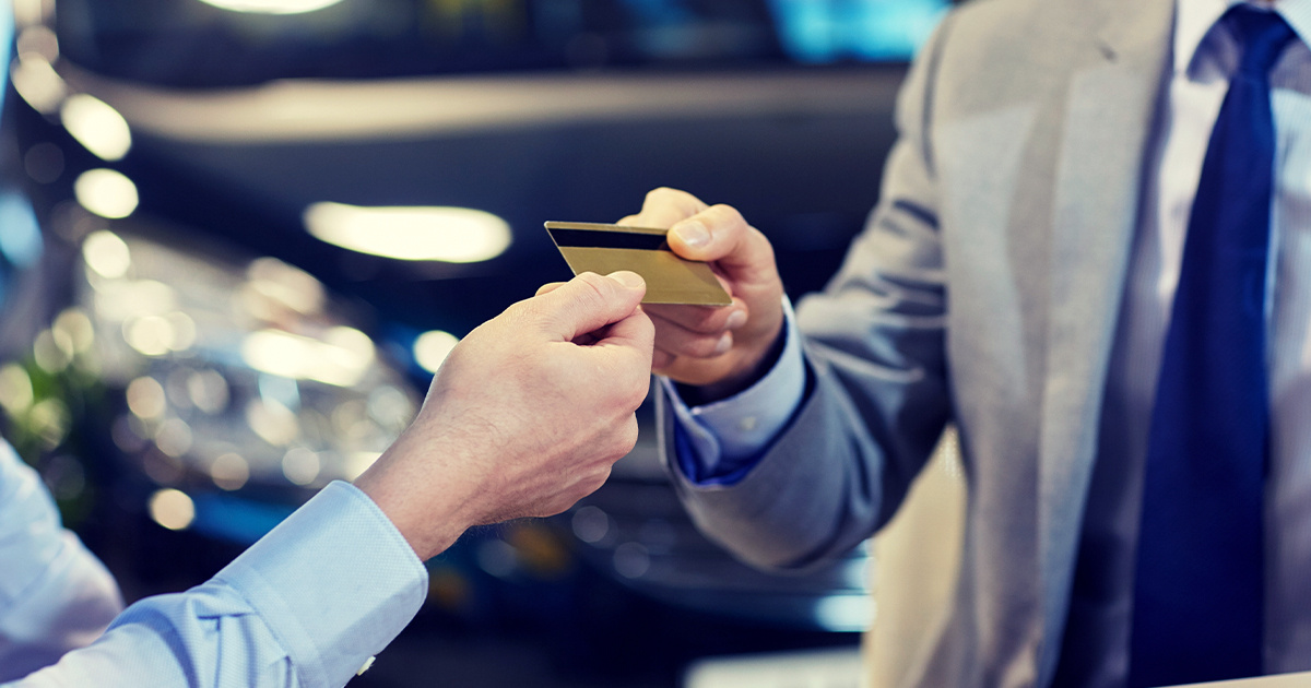 Customer handing credit card to salesman wearing a suit.